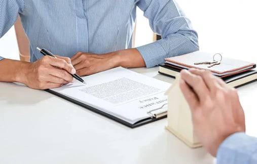 manos firmando contrato de compraventa con reserva de dominio para comprar una casa 