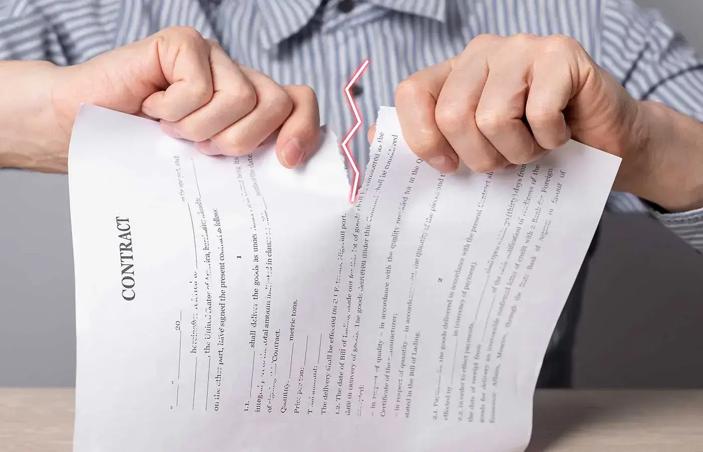 alt: manos de persona rompiendo contrato por incumplimiento de contrato de compraventa